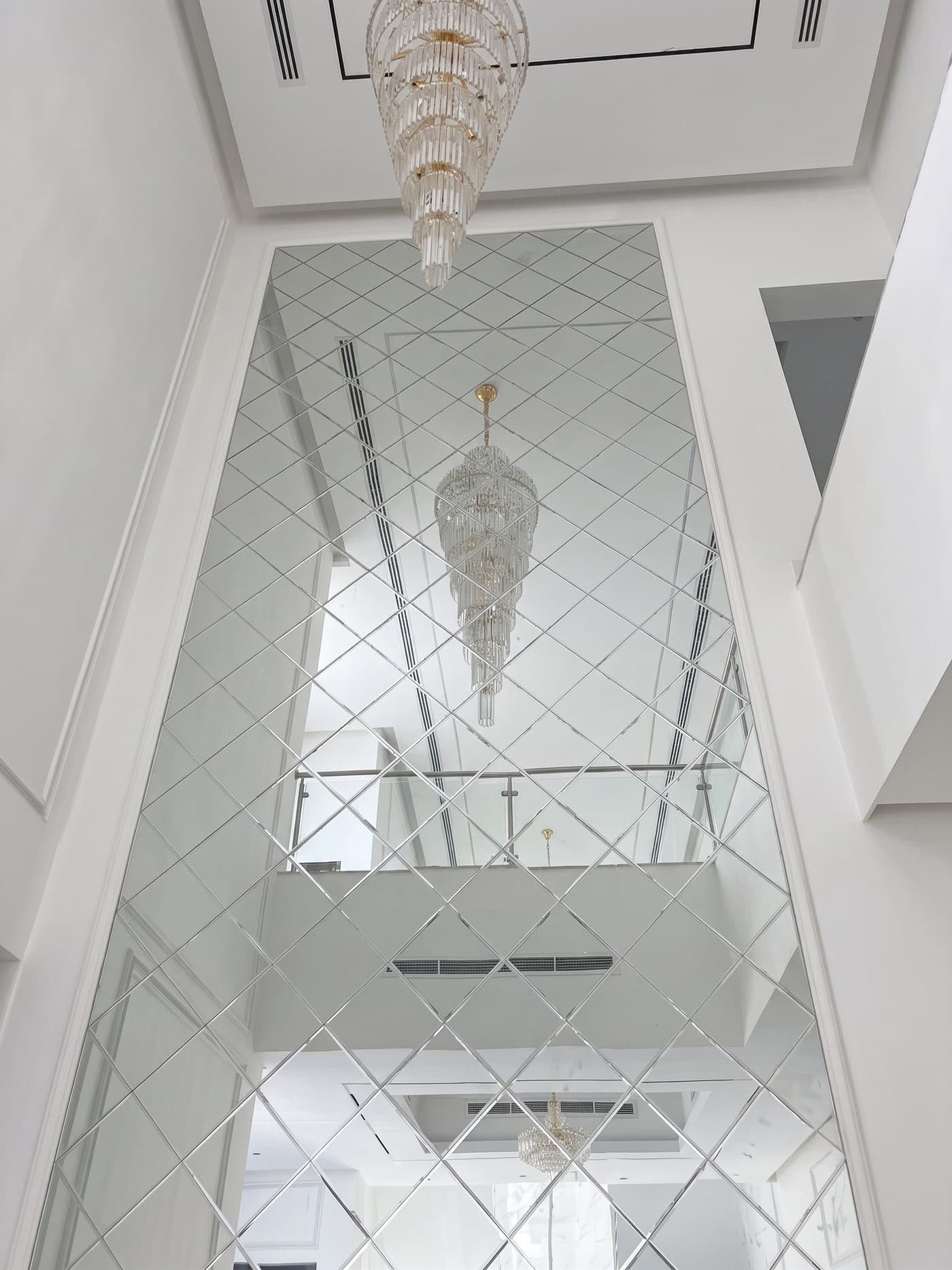 A mirrored atrium wall reflecting the double-height space in front of it.