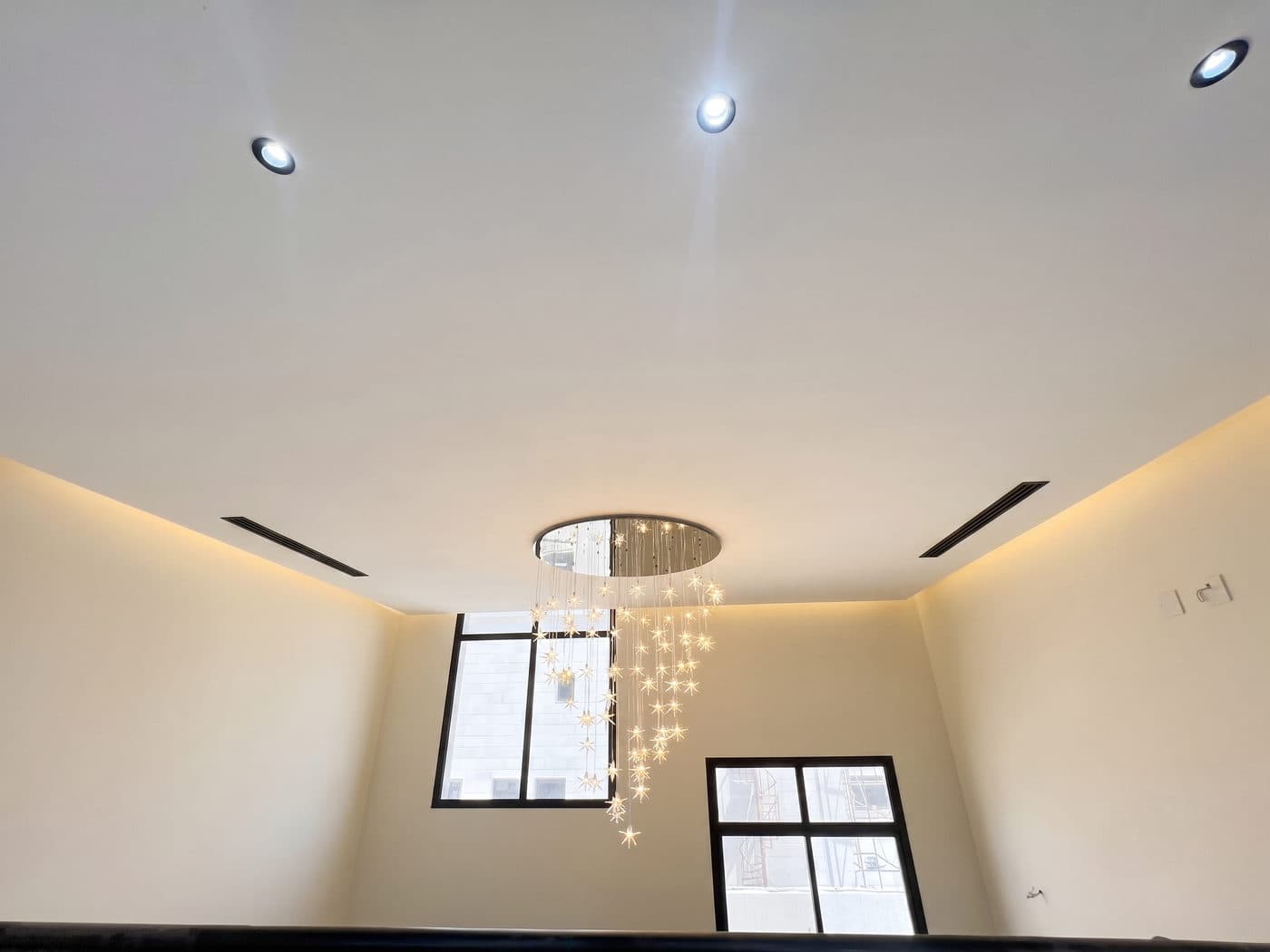 The cascading droplet chandelier beneath a cove-lit ceiling