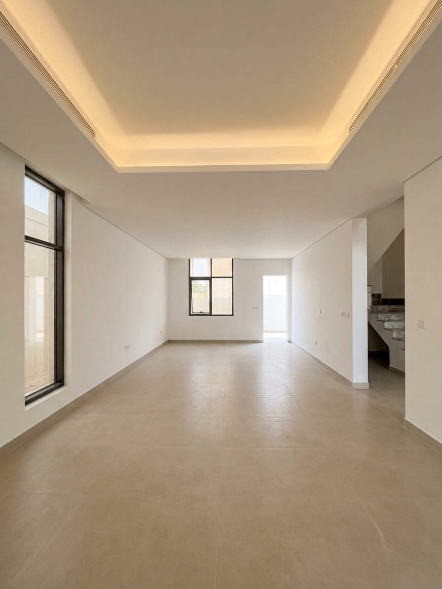 A warm minimal living room beneath a stepped cove ceiling