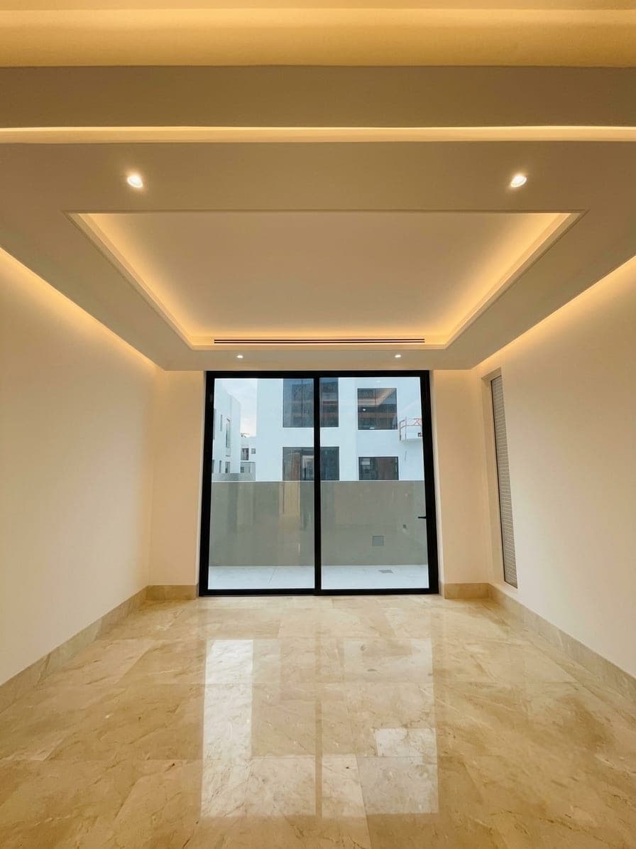 A room finished in marble flooring, opening to a window