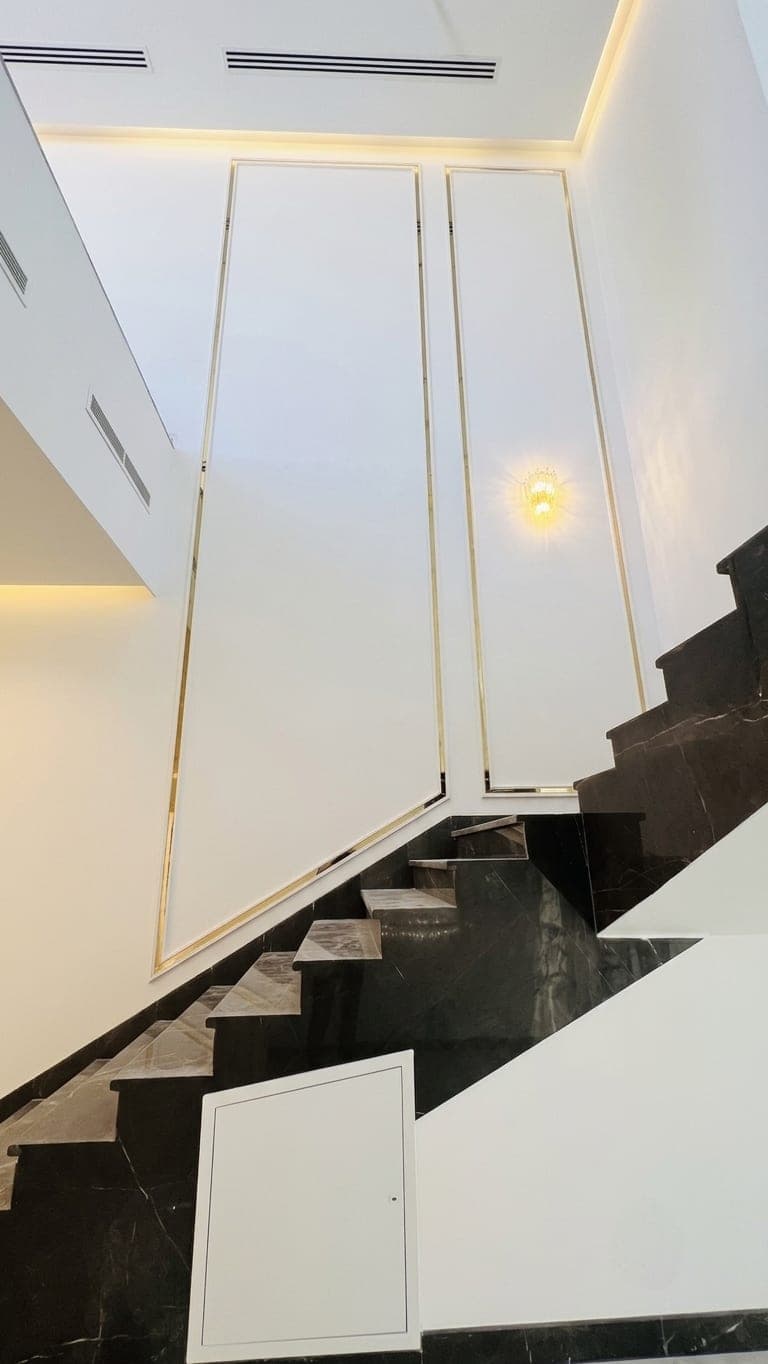 The dark marble staircase set against brass-framed white wall panels