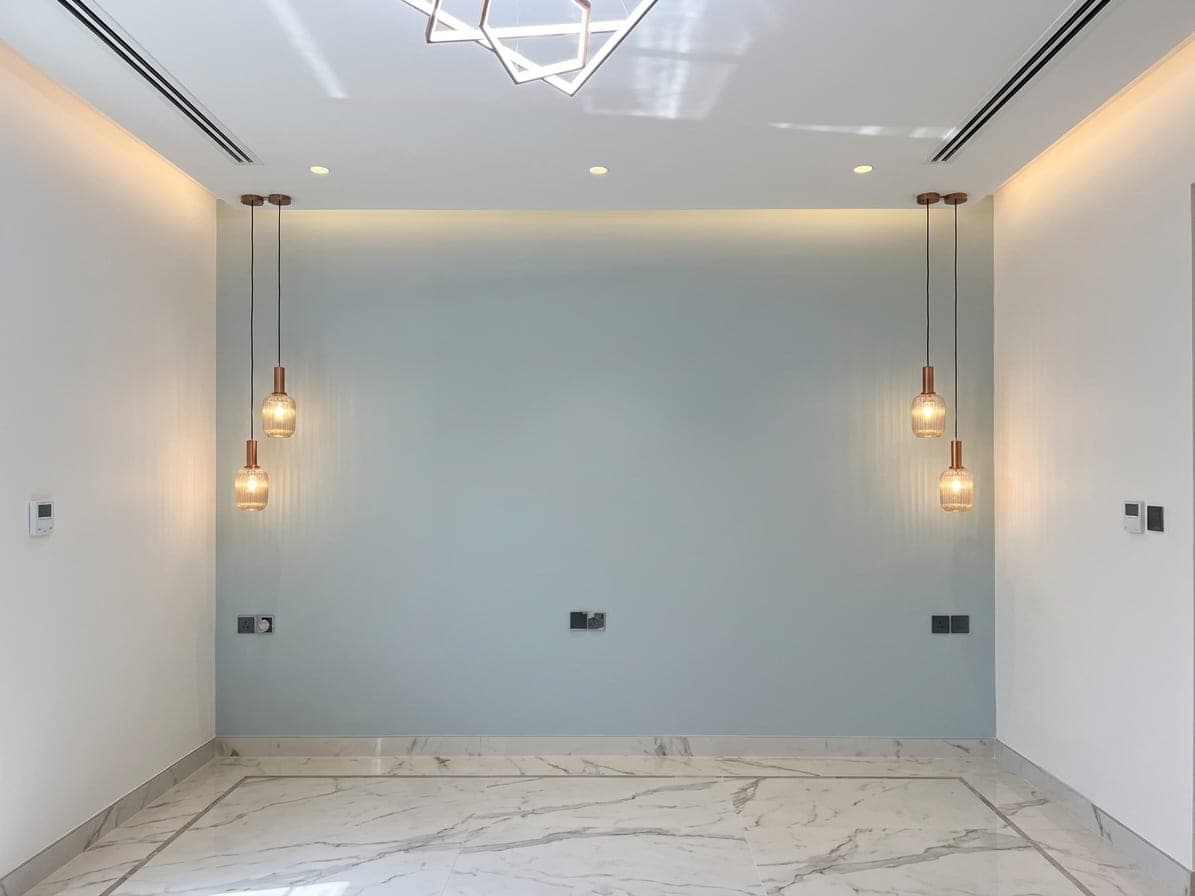 A blue feature wall with suspended glass pendants over a marble floor
