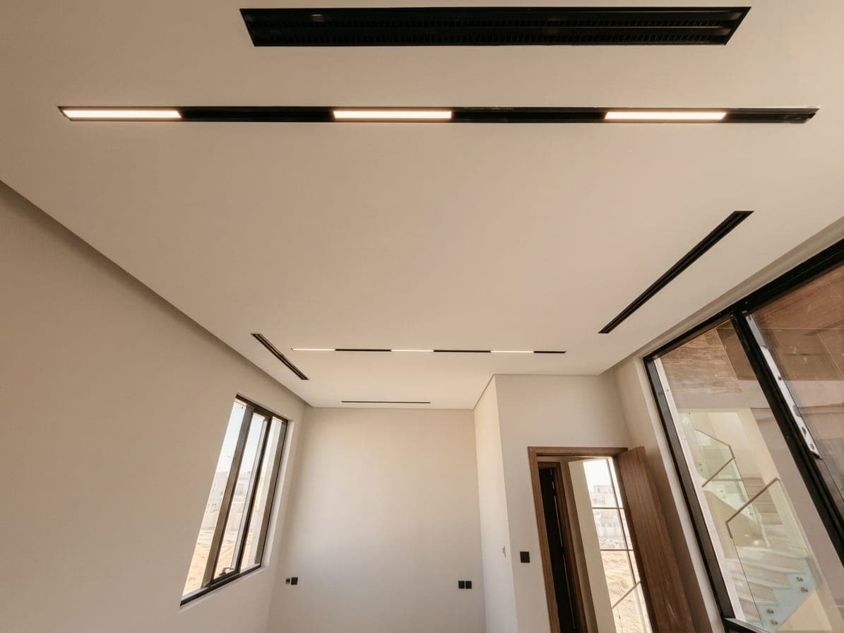Black linear light lines set into the ceiling, beside black-framed glazing