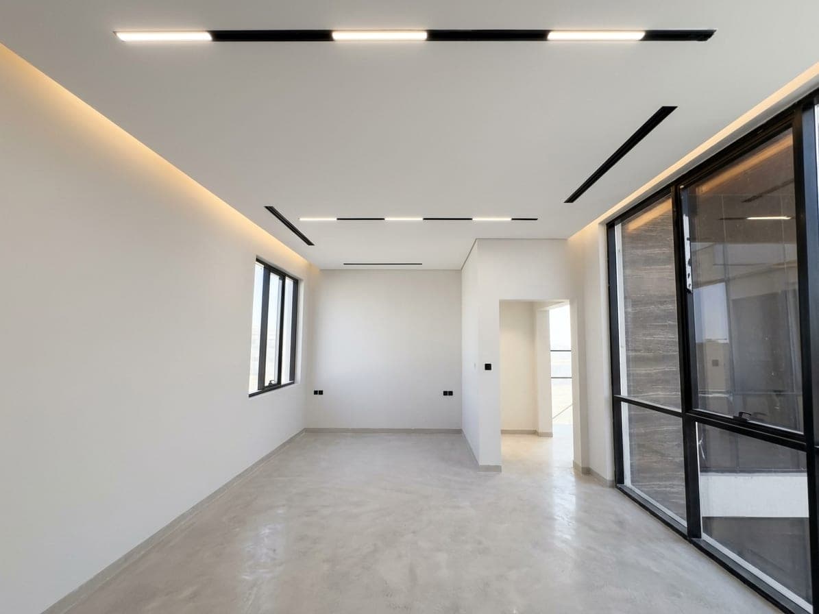 The room opening to a corridor through full-height black-framed glass