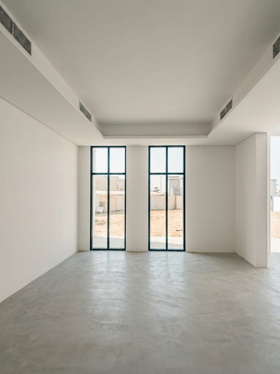 A room finished in seamless polished flooring, with paired full-height windows