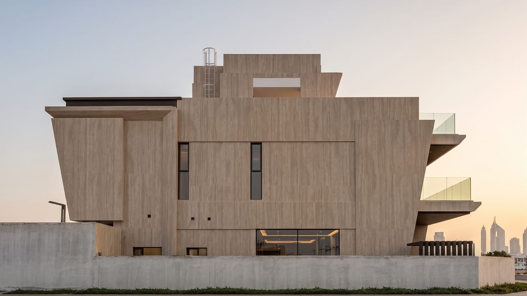 The elevation at dusk, with the interior lighting visible through the glazing