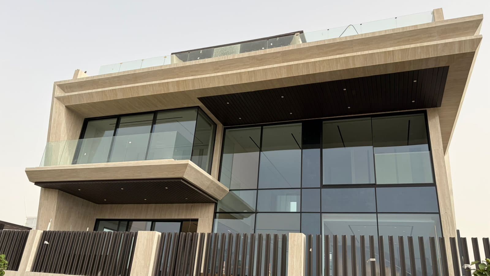 The villa's front elevation, clad in travertine with full-height glazing
