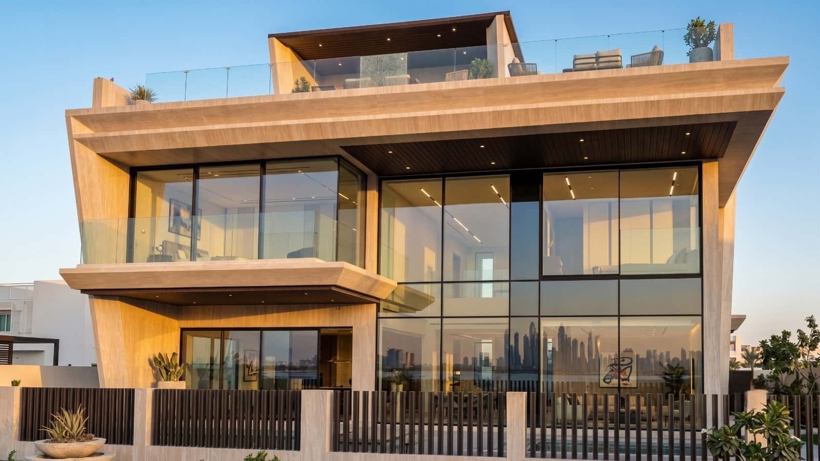 Travertine-clad villa in Dubai at dusk, its double-height glazing lit from within.